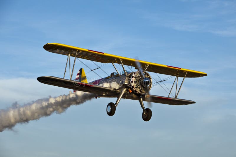 Yellow biplane with smoke. stock photo