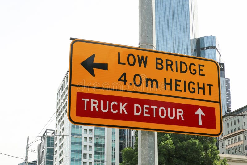 A yellow and black â€™Low Bridge` and â€˜Truck Detour` sign