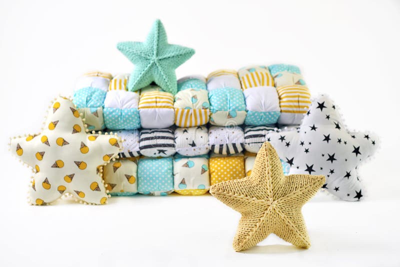 Yellow and blue-green knitted and stitched five-pointed star shaped pillows and patchwork comforter on white background.