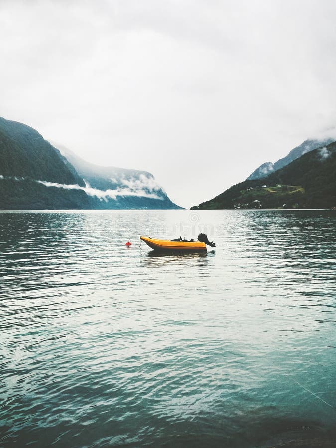 Yellow boat in sea fjord and foggy Mountains Landscape