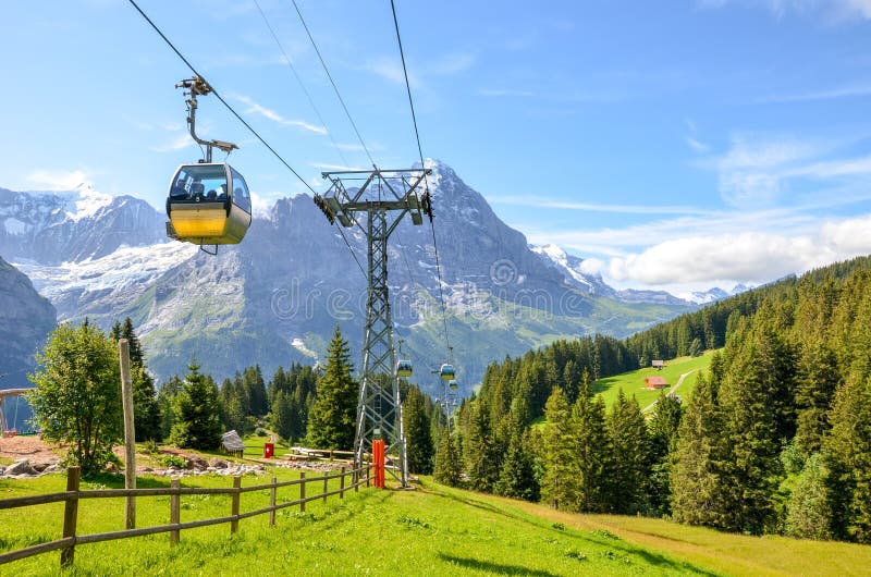 Yellow cable car in the Swiss Alps. Gondola going from Grindelwald to First in the Jungfrau area. Summer Alpine landscape with