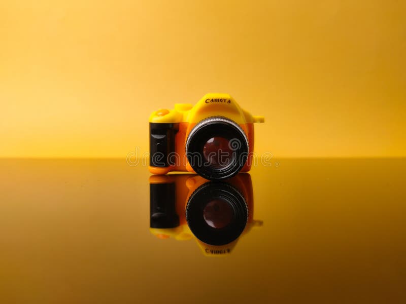 Yellow camera on yellow background with reflection stock photo