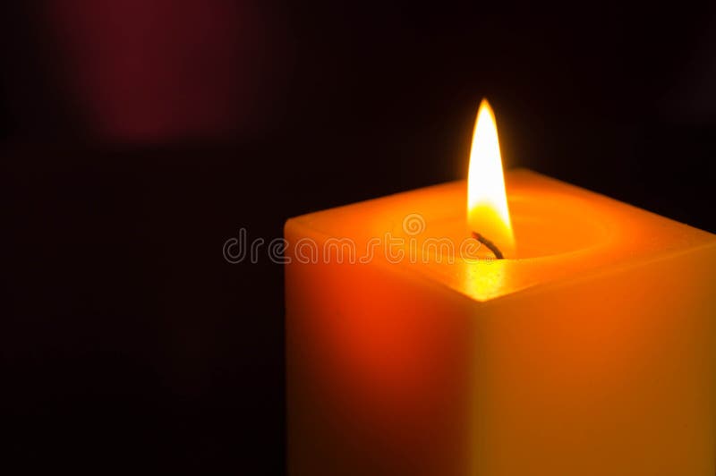 The yellow candle burning in the dark