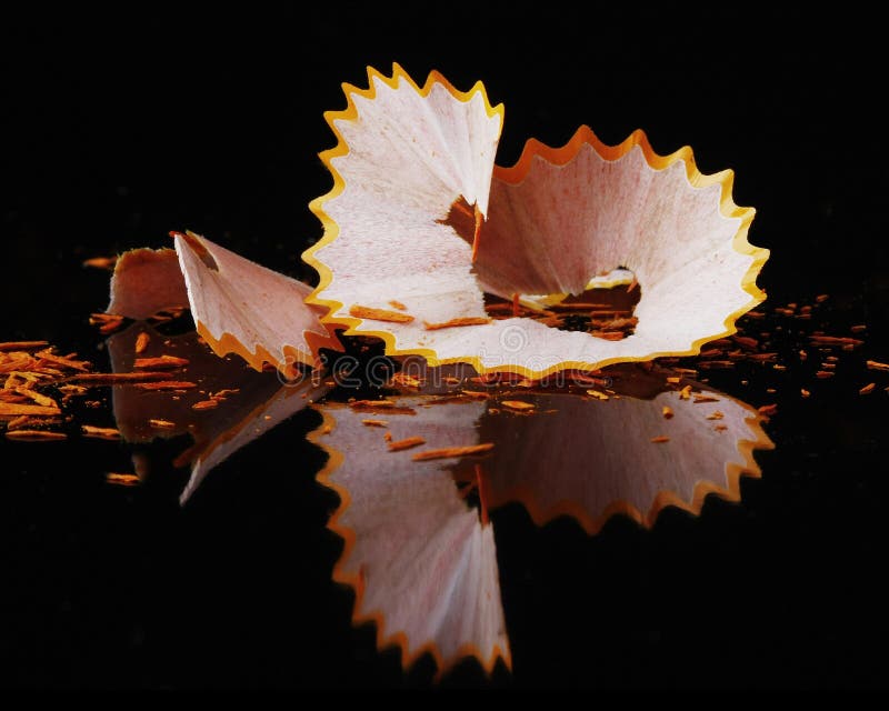 Yellow colured pencil shaving on black reflective