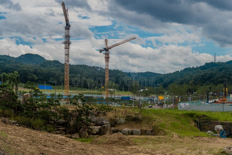 Yellow construction cranes at project site under cloudy sky