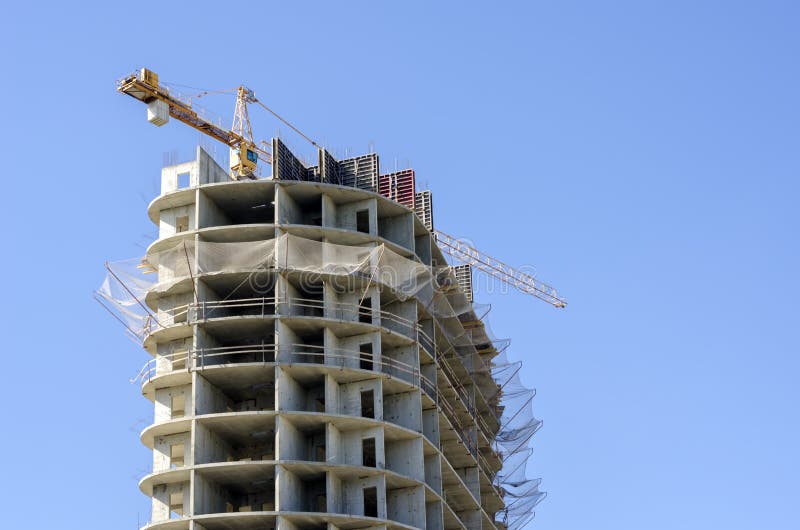 Yellow crane over high-rise building under construction close-up royalty free stock photo Yellow crane over high-rise building under construction close-up royalty free stock photo