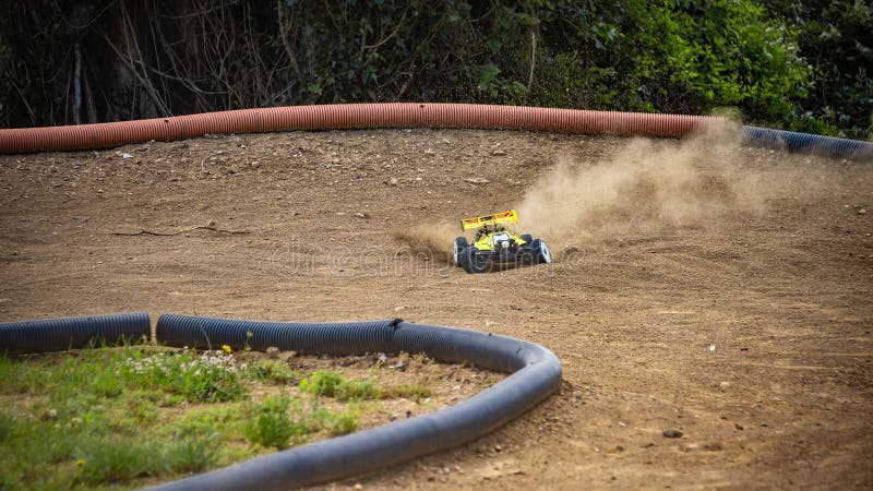 Žlutá elektrická RC bugina závodící na offroadové venkovní dráze