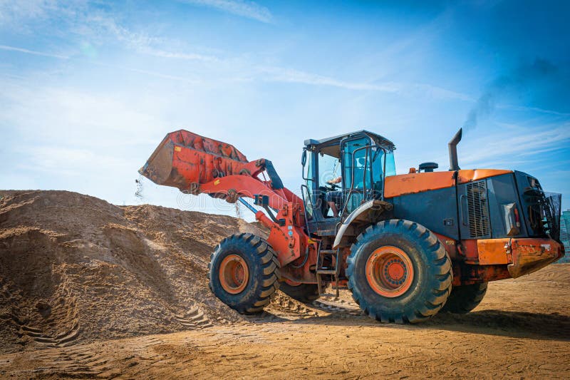 Yellow excavator on a construction site against blue sky. wheel loader at sandpit during earthmoving works