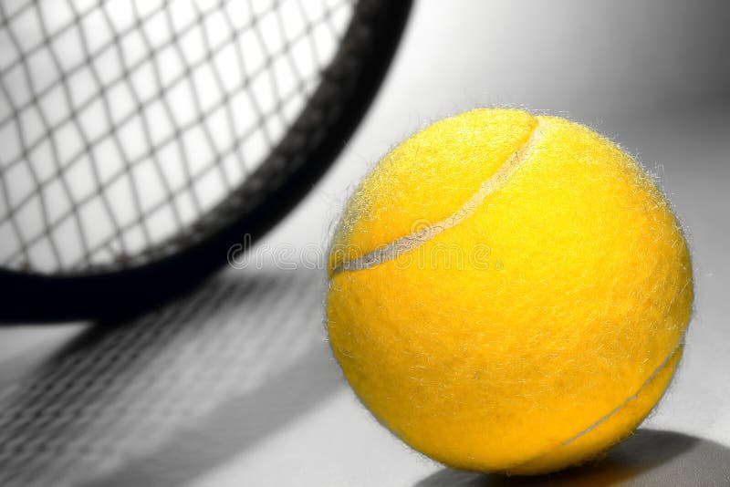 Bright yellow felt regulation championship tennis ball and sport racket on smooth court surface. Bright yellow felt regulation championship tennis ball and sport racket on smooth court surface