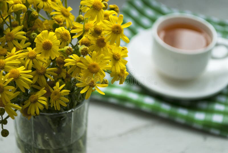 Yellow Flowers and a Cup of Herbal Tea in the Background Stock Photo