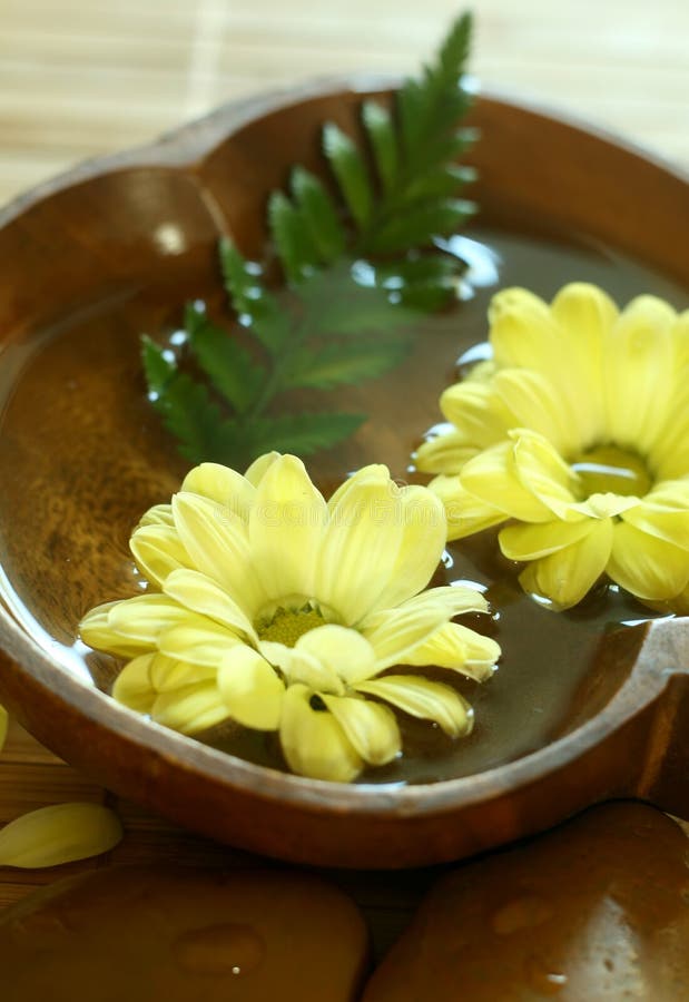 Yellow flowers floating in wooden bowl.