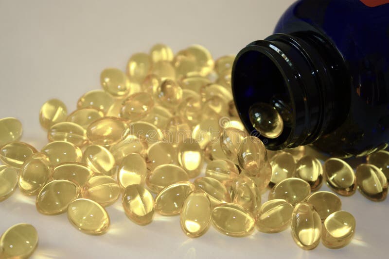 Yellow gelatin capsules omega 3 poured from dark pharmaceutical bottle.