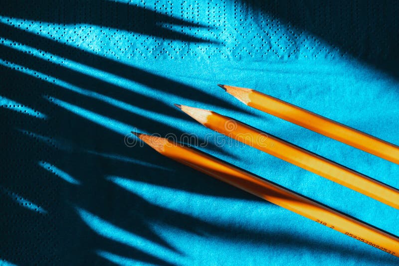 Yellow graphite pencils on a blue background, top view. hard shadows. stock photos