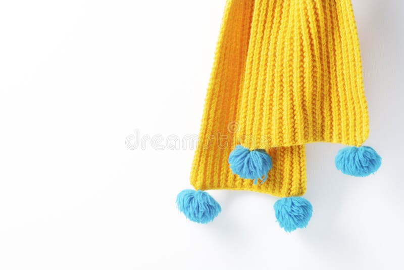Yellow Knitted Scarf Hanging on a White Background. Closeup, Selective