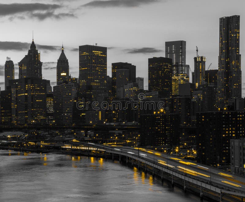 Yellow lights shining in black and white cityscape with the downtown Manhattan skyline buildings of New York City at night time