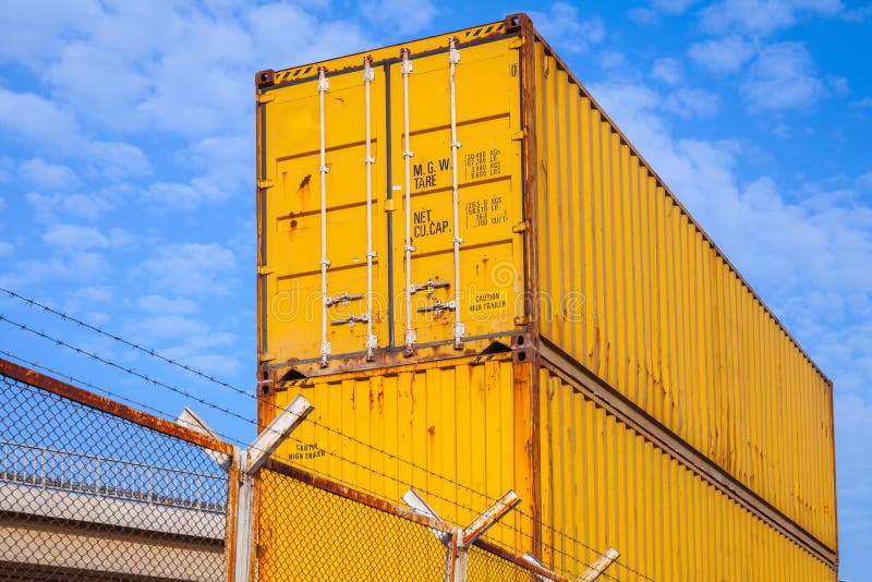 Yellow metal Industrial cargo containers are stacked under blue cloudy sky