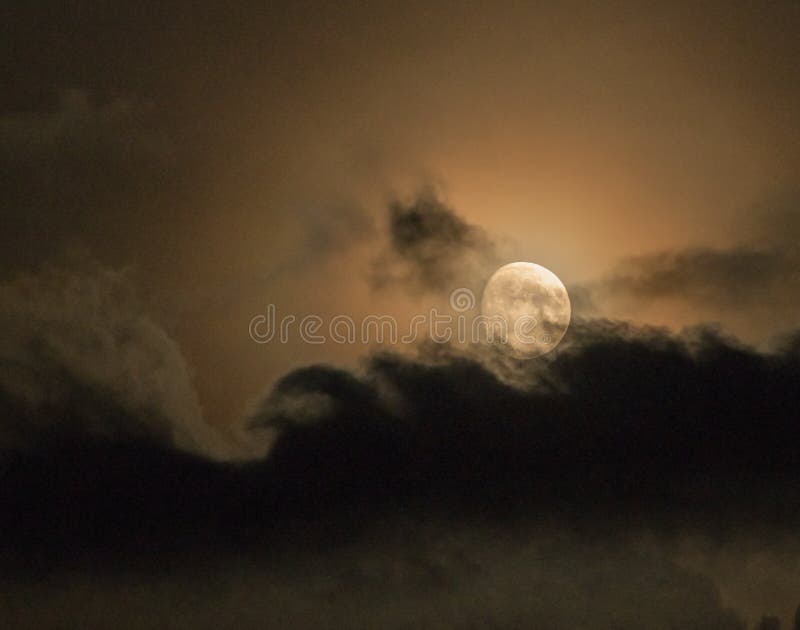 Yellow moon between heavy clouds in the night sky royalty free stock photo