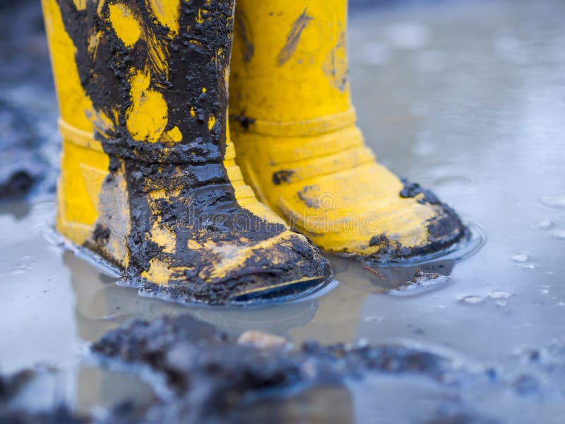 Yellow muddy boots in puddle. Yellow muddy boots in puddle