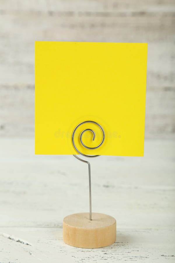 Yellow note paper on a holder on white wooden background. stock photos