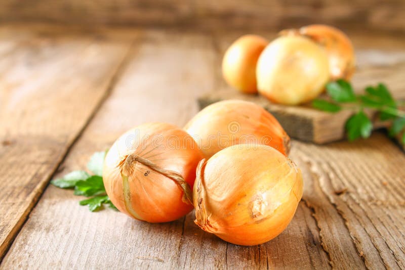 Yellow onion with parsley on a wooden table.