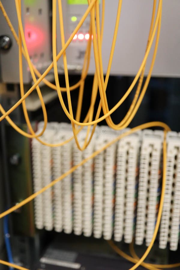 Yellow optical fiber network cable with blue connectors with the equipment on the background stock photography