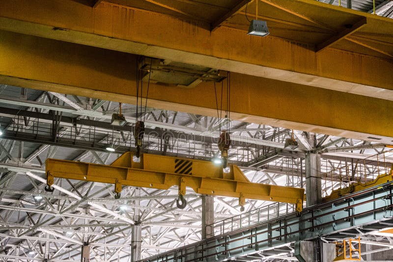 Yellow overhead crane. Jib crab trolley with hooks.