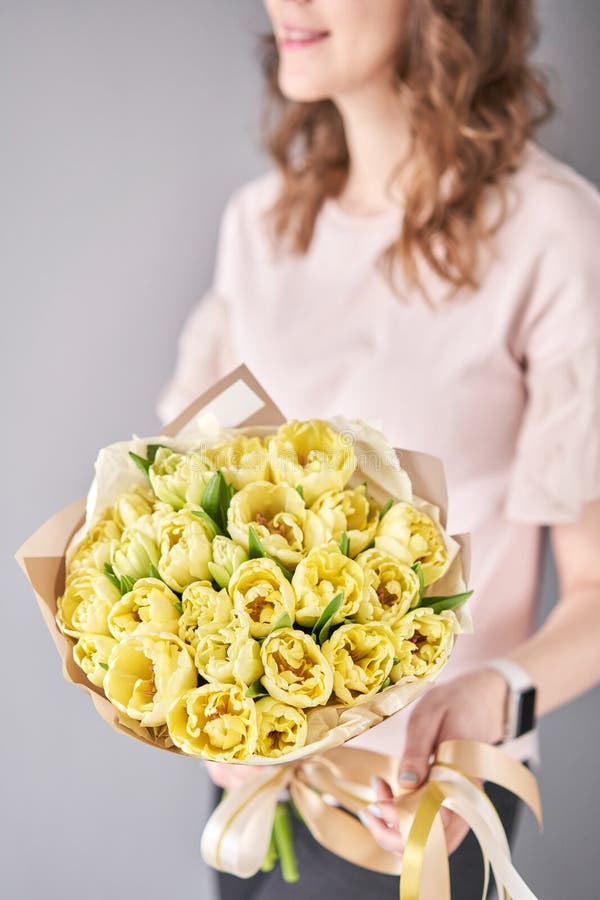 Yellow pastel color tulips in woman hand. Young beautiful woman holding a spring bouquet. Bunch of fresh cut spring