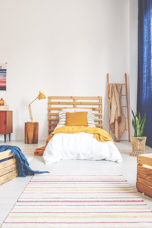 Yellow pillow and blanket on comfortable white wooden bed in teenager bedroom with stripped carpet on the floor royalty free stock photos Yellow pillow and blanket on comfortable white wooden bed in teenager bedroom with stripped carpet on the floor royalty free stock photos