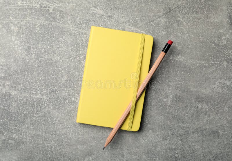 Yellow planner and pencil on grey table, top view royalty free stock photo
