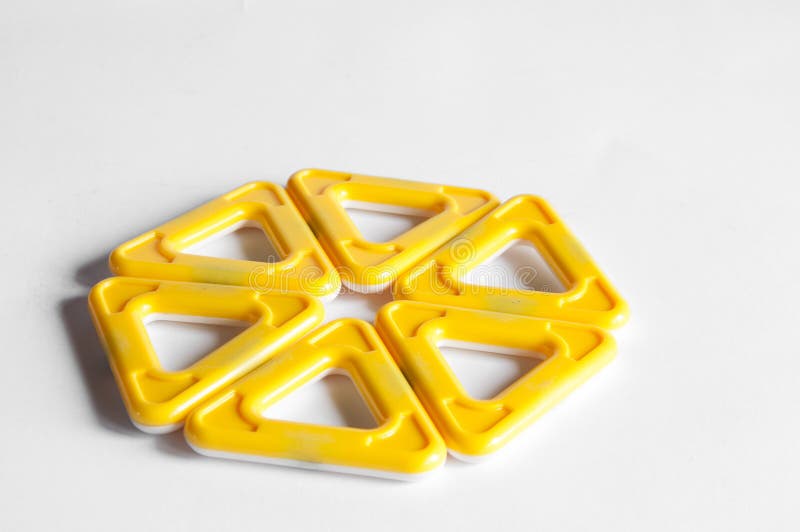 Yellow plastic children`s designer with magnets. On white background. Triangles and squares