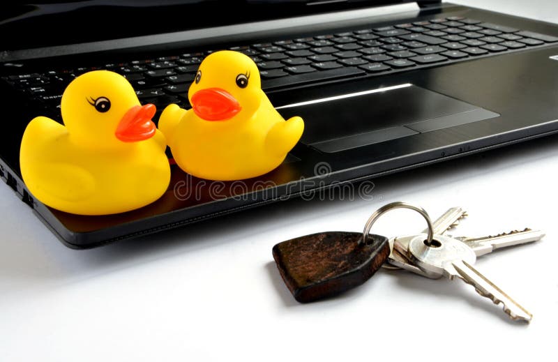 Yellow Plastic Ducks Sit on Notebook Computer Next To Keys To House