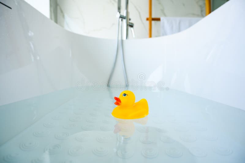 Yellow playful rubber duck float in the bathtub. Kids bath time concept. Funny toy for kits