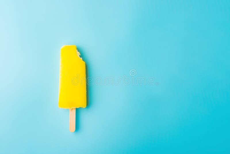 Yellow popsicle with a bite on a blue background. Yellow popsicle with a bite on a blue background