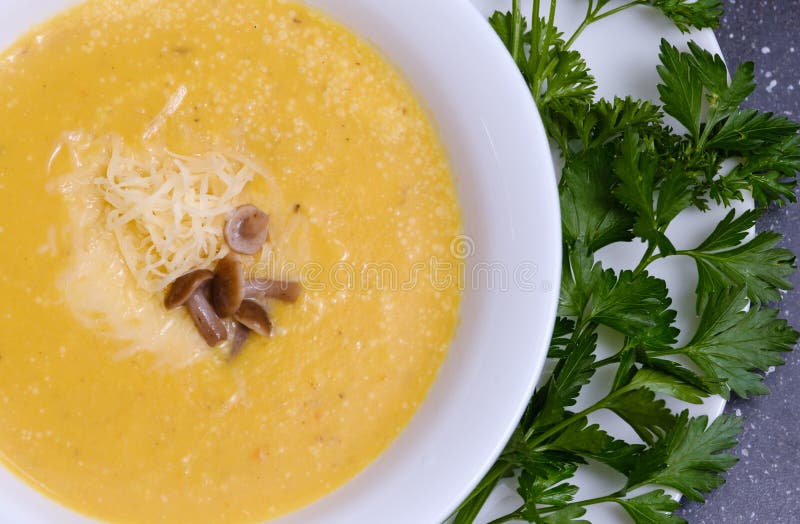 Yellow Pumpkin Soup with Mushrooms in a Plate on the Table Stock Photo
