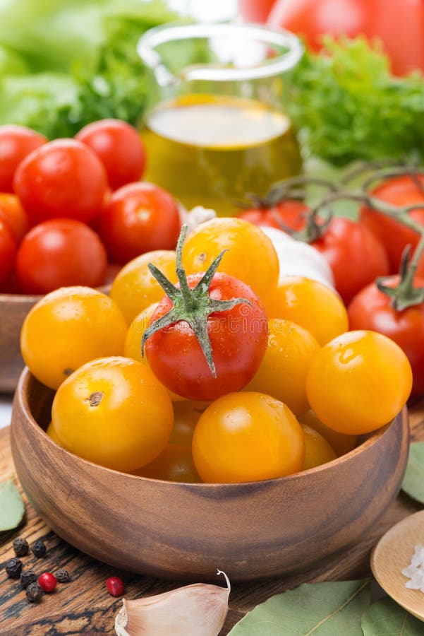 Yellow and red cherry tomatoes in wooden bowls, close-up, vertical