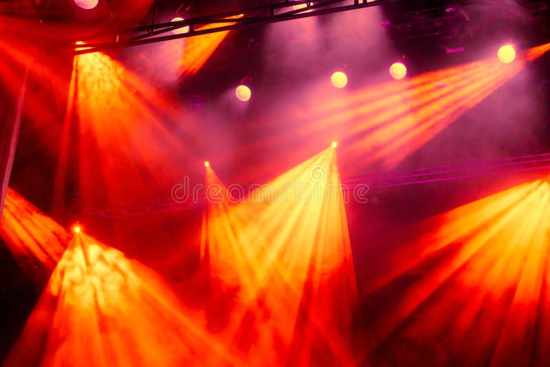 Yellow and red light rays from the spotlight through the smoke at the theater or concert hall. Lighting equipment