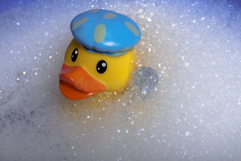 A Yellow Rubber Duck for a Bath in a Bath Cap and with a Shower Head in