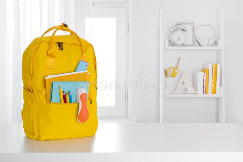 Yellow school backpack on table over children room interior royalty free stock photography
