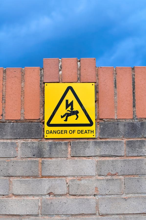 Yellow sign danger of death on the brick fence copy space. High quality photo