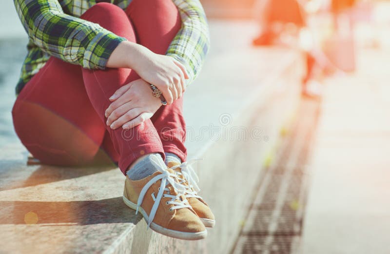 Yellow sneakers on girl legs in hipster style sitting on the bench