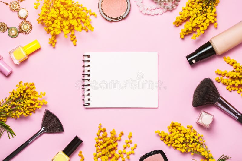 Yellow spring flowers, notebok and some cosmetics on pink trendy background, top view, flat lay. Copy space for text. Yellow spring flowers, notebok and some cosmetics on pink trendy background, top view, flat lay. Copy space for text