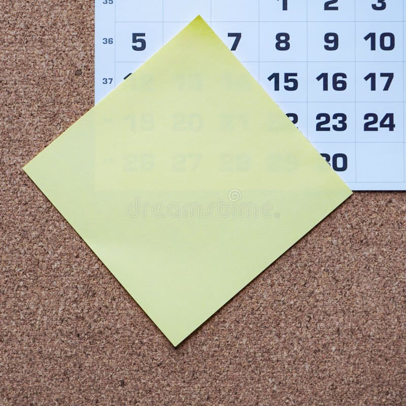 Yellow Sticky Note with a Calendar Pad in the Background Stock Photo