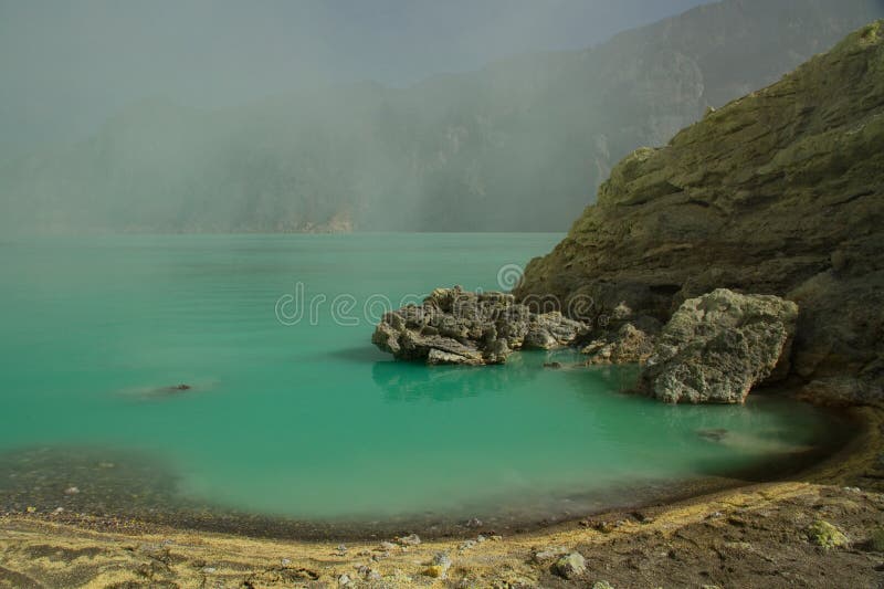 Yellow sulfur mine with blue lake inside volcano royalty free stock image