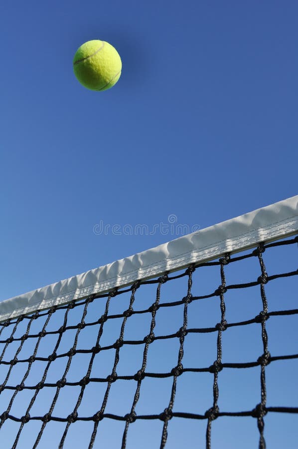 Yellow Tennis Ball on Tennis Racquet Against a Light Stock Photo