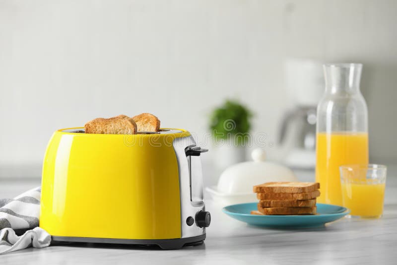 Yellow Toaster with Roasted Bread Slices and Orange Juice on White