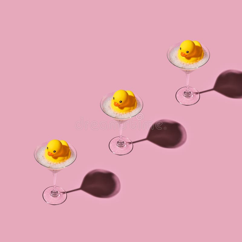 Yellow toy rubber duck floating in a martini glass with bubble foam. Creative abstract drinking in bath royalty free stock photo