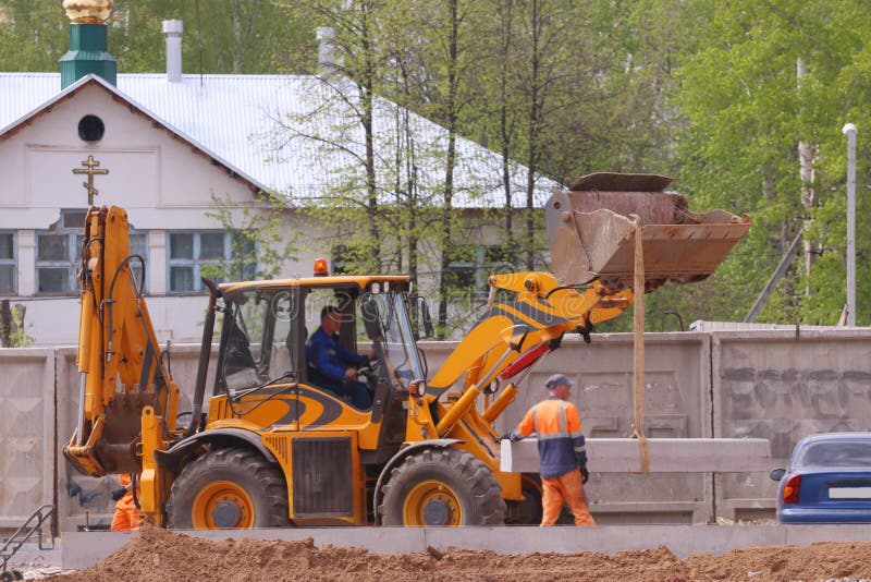 Yellow Tractor and Worker on Construction Site at Spring Day Editorial