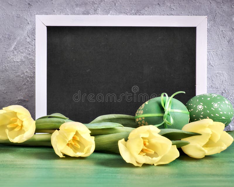Yellow tulips, blackboard with caption \'Happy Easter\' and and decorative eggs royalty free stock photography