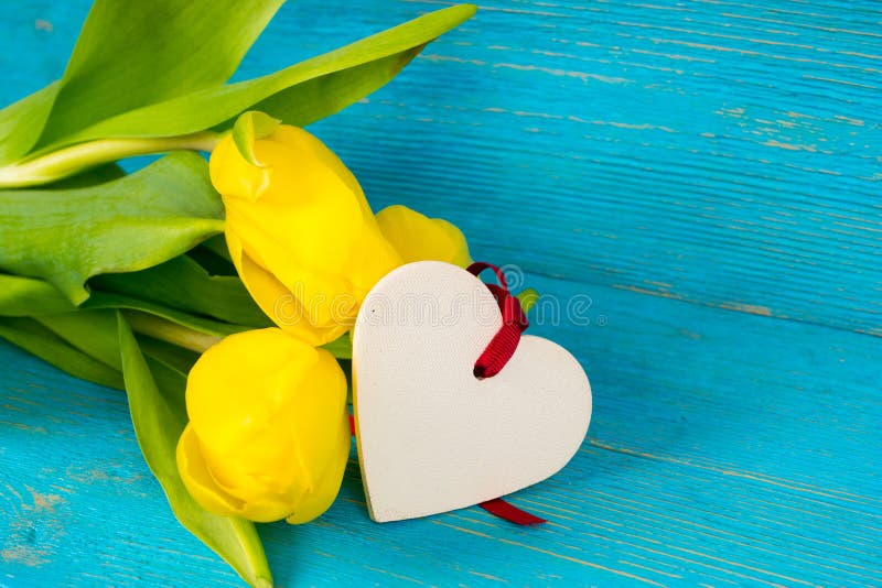 Yellow tulips bouquet with heart shape on turquoise wooden background stock image Yellow tulips bouquet with heart shape on turquoise wooden background stock image