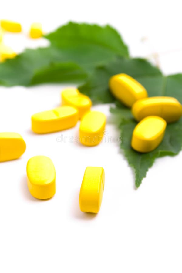 Yellow vitamin pills over green leaves on white background. Green herbal drug medicine stock images, royalty-free photos and pictures
